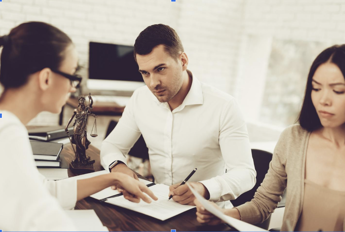 Husband and wife signing documents with a lawyer