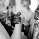 Two people, one of white race and one of black race, clasping hands, black and white photo.