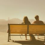 Couple sitting on bench looking to ocean