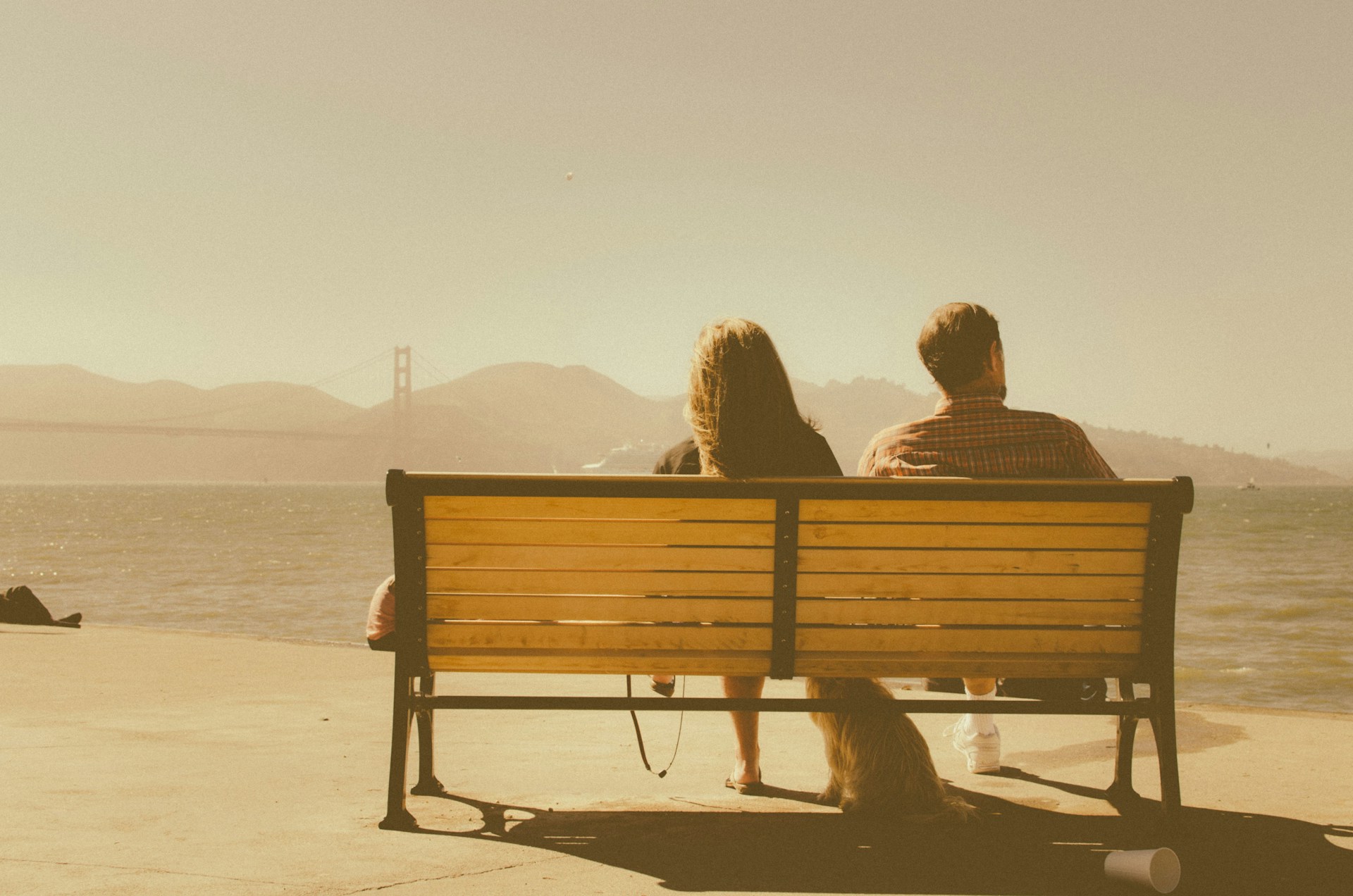 Couple sitting on bench looking to ocean