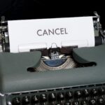 Grey old-fashioned typewriter with white page and black text "Cancel"