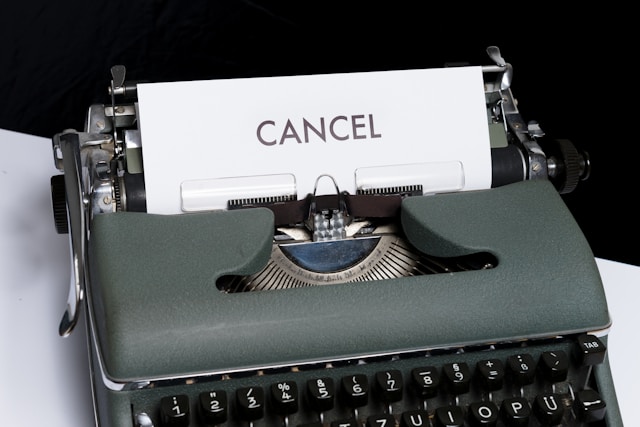 Grey old-fashioned typewriter with white page and black text "Cancel"